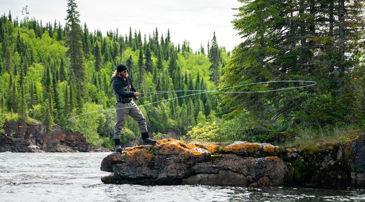 A fly fisherman standing on a rock