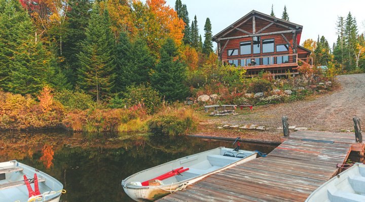 Chalet devant un lac et chaloupe.