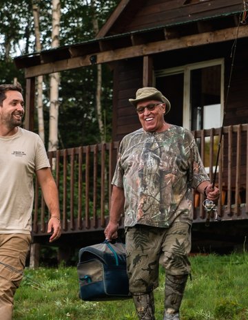 An outfitter and his client in front of a cottage