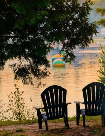 Deux chaises de camping devant un feu et un lac