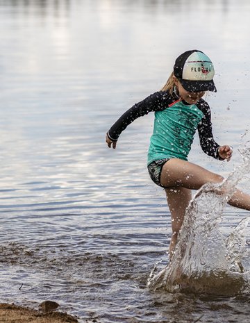 A child plays on the shore of an outfitter's lake.