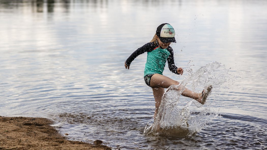 A child plays on the shore of an outfitter's lake.