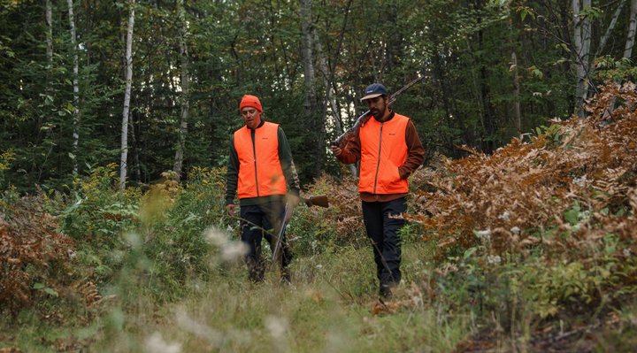 Hunting in outfitters Two hunters walking in the forest.
