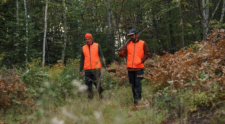 Two hunters walking in the forest.