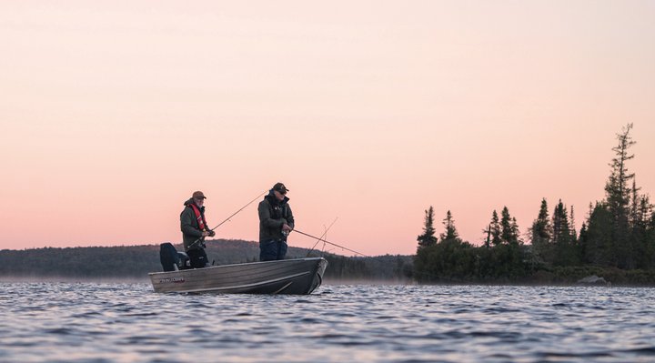 Two fishermen in a rowboat on a large lake.