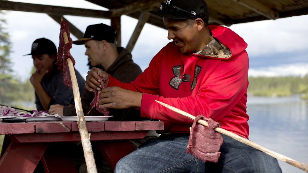 Un homme autochtone prépare de la viande.