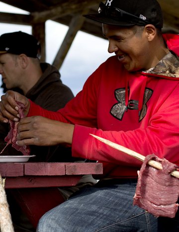 Un homme autochtone prépare de la viande.