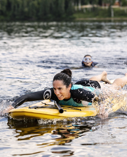 Woman on a paddle board swimming with her hands.