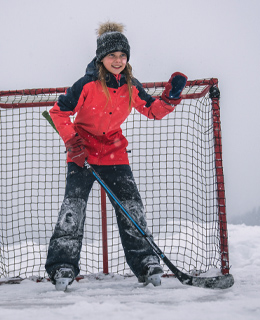Girl skating in front of a hockey goal on an icy lake.
