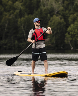 A man standing on a paddleboard on a lake.